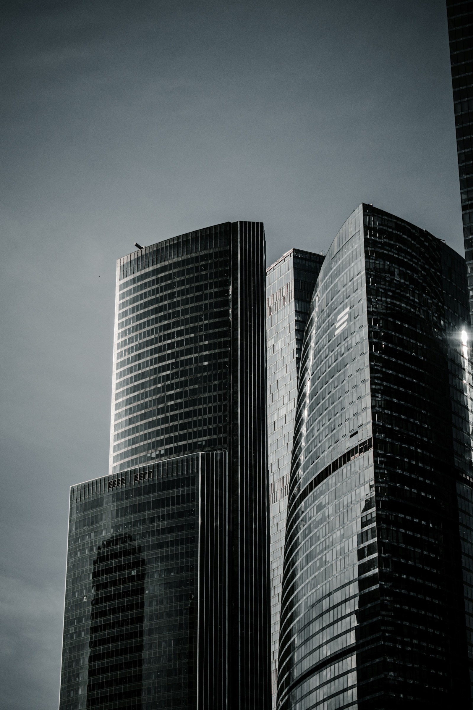 Cluster of dark glass-clad residential towers under a moody sky