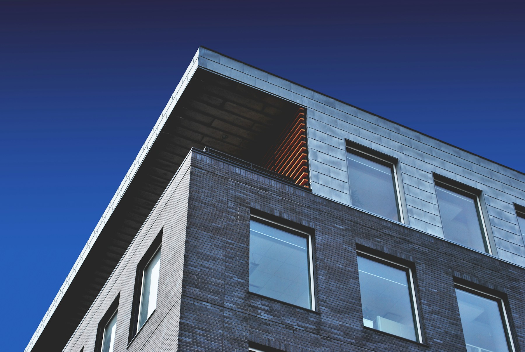 Modern dark-stone residential tower under a deep sky